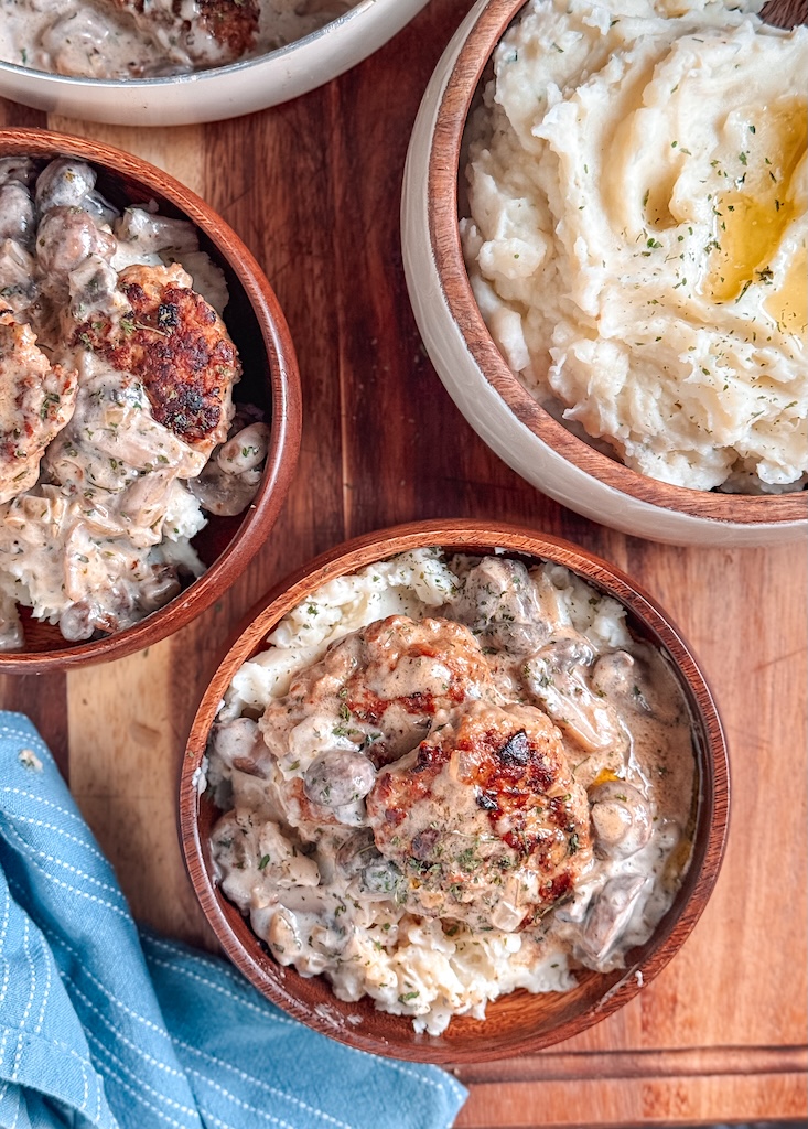 Golden brown turkey patties simmering in creamy mushroom sauce with sliced mushrooms
