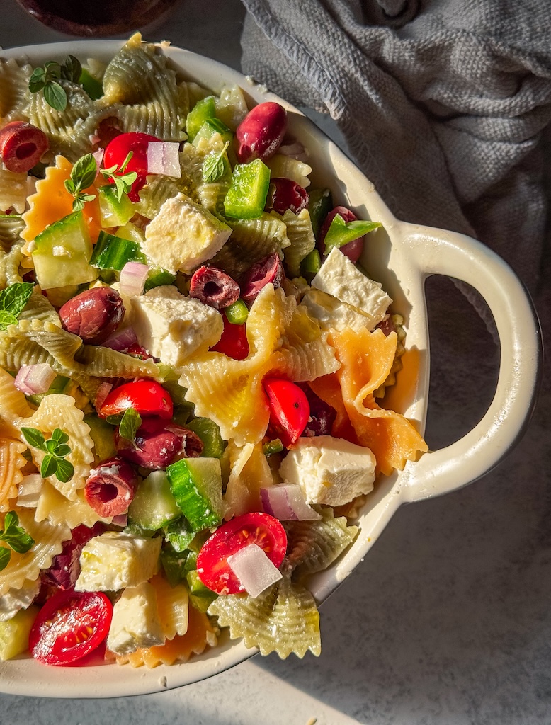 Fresh Greek-inspired pasta salad made with bow tie pasta, cucumbers, tomatoes, feta, olives, and homemade lemon dressing.