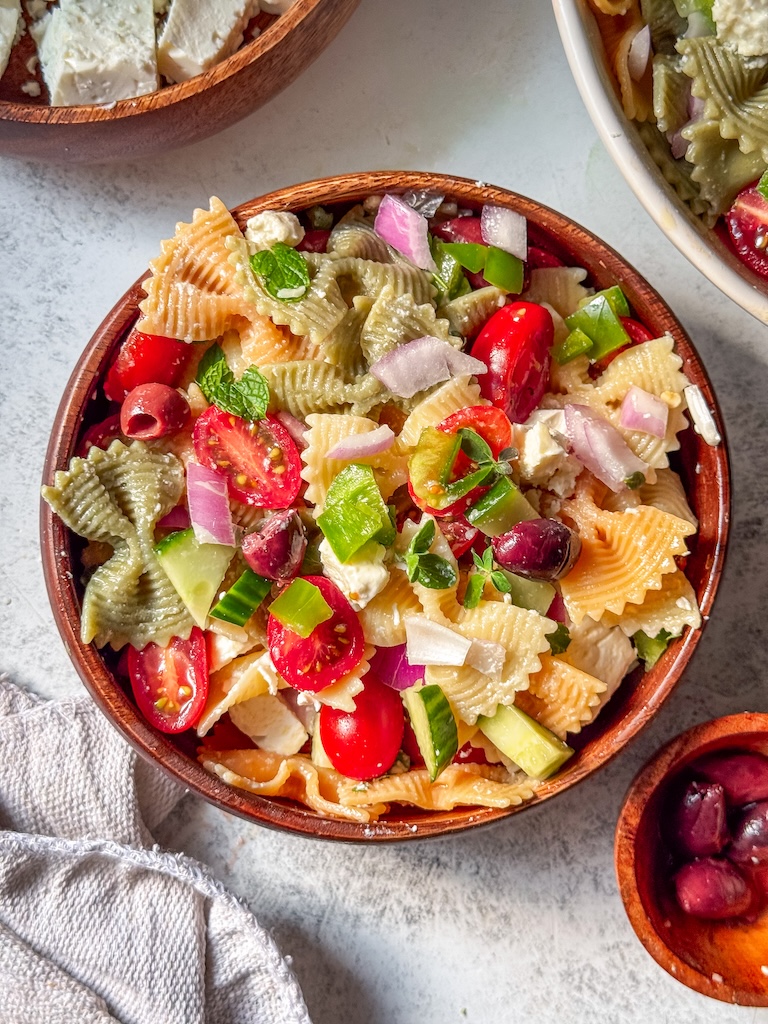 Mediterranean-inspired pasta salad with farfalle, feta cheese, fresh mint, oregano, tomatoes, and cucumbers.