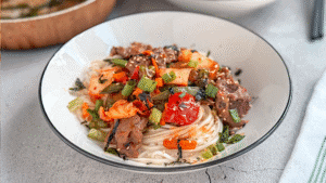 Beef and kimchi yakisoba noodles with vegetables and sesame seeds in a bowl — a quick and flavorful Asian stir-fry recipe.