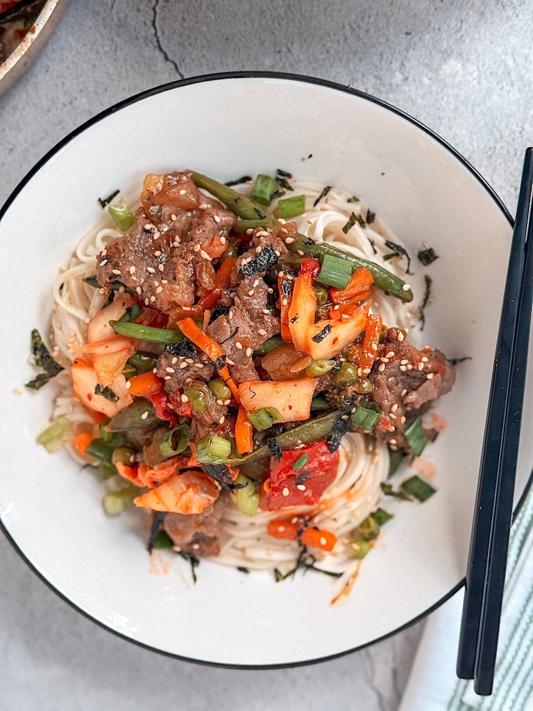 Beef and kimchi yakisoba with vegetables and sesame seeds.