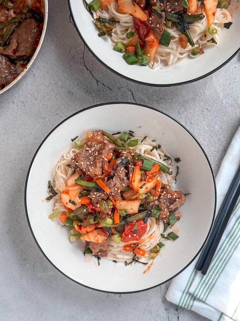 Beef and kimchi yakisoba noodles with vegetables and sesame seeds in a bowl — a quick and flavorful Asian stir-fry recipe.