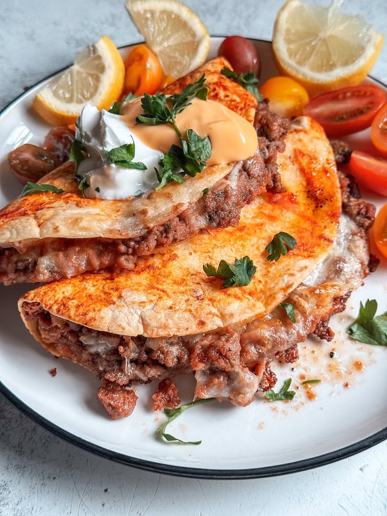 Baked beef and bean soft tacos with melted cheese and taco sauce