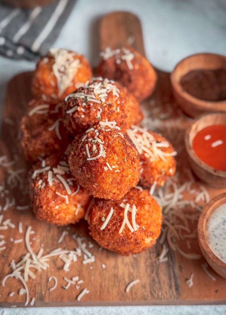 Golden brown fried mac and cheese balls stacked on a plate