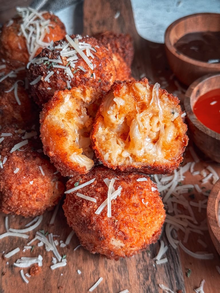 Golden brown crispy fried mac and cheese balls stacked on a plate