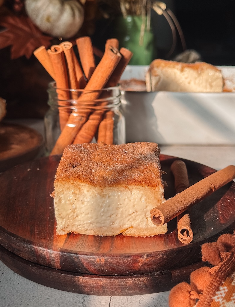 Churro cheesecake bar with thick vanilla cheesecake filling and cinnamon-sugar crescent pastry.